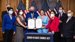 U.S. House Speaker Nancy Pelosi, a Democrat from California, center right, and Senate Majority Leader Chuck Schumer, a Democrat from New York, center left, display the Covid-19 Hate Crimes Act after the signing during a bill enrollment ceremony at the U.S. Capitol in Washington, D.C., U.S., on Wednesday, May 19, 2021.