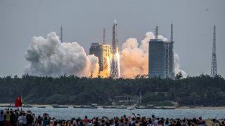 People watch a Long March 5B rocket, carrying China's Tianhe space station core module, as it lifts off from the Wenchang Space Launch Center in southern China's Hainan province on April 29, 2021.