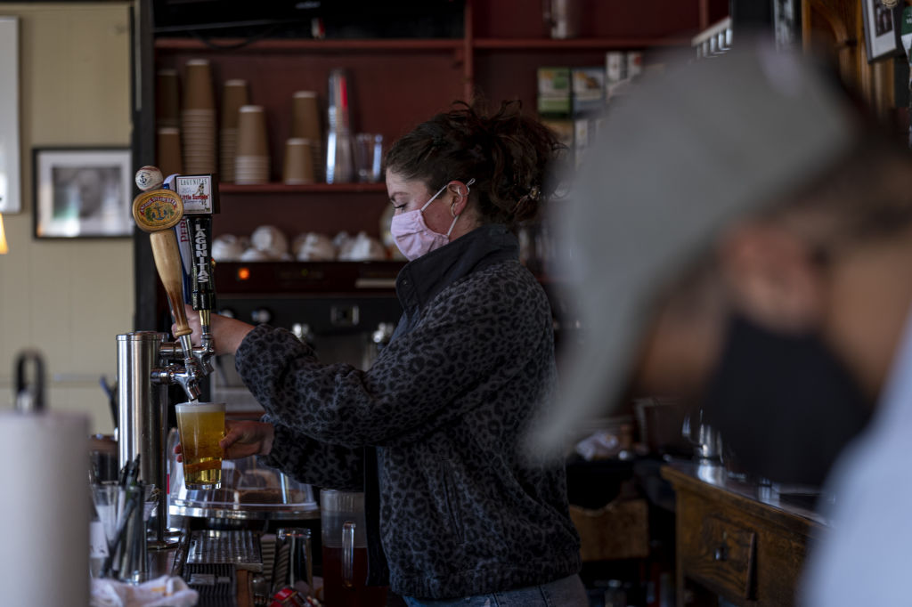 A worker wearing a protective mask pours a beer inside a restaurant in San Francisco, California, U.S., on Thursday, May 6, 2021. San Francisco advanced into the least restrictive tier of Californias color-coded reopening system Tuesday, allowing most businesses to expand capacity, bars to start serving indoors and large gatherings to resume inside and outside. Photographer: David Paul Morris/Bloomberg via Getty Images