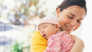 Mother carrying sleeping baby girl