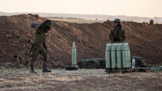 Israeli soldier arms artillery shells next to an artillery unit, at the Israeli Gaza border, Wednesday, May 19, 2021.