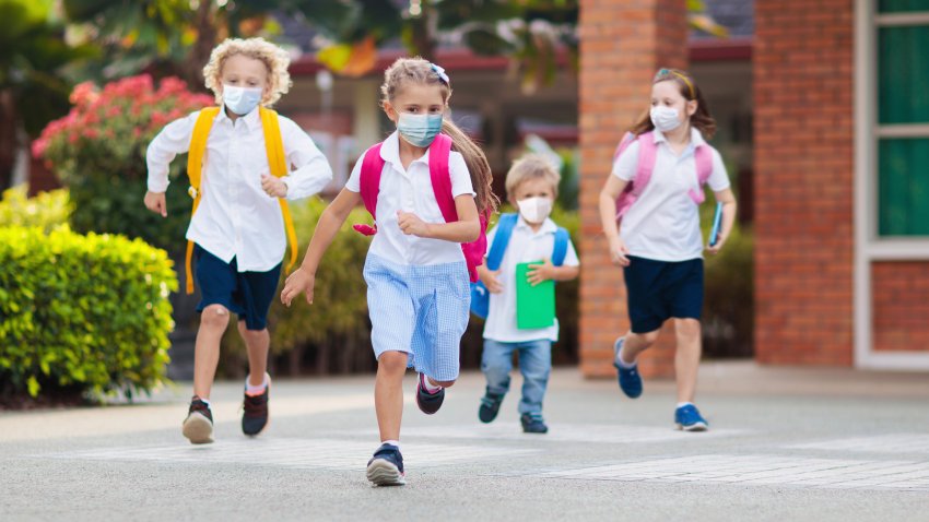 School child wearing face mask during corona virus and flu outbreak. Boy and girl going back to school after covid-19 quarantine and lockdown. Group of kids in masks for coronavirus prevention.