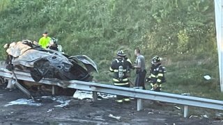 a burned and heavily damaged car resting on a guardrail after a crash in Rocky Hill