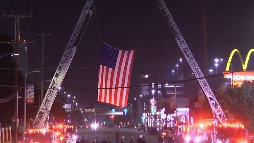 Firefighters saluted a colleague Tuesday night as the body of a slain colleague killed in a shooting was transported in a solemn procession from Fire Station 81 in the Santa Clarita Valley to the coroner's office near downtown Los Angeles.