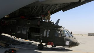 Aerial porters and maintainers load a helicopter.