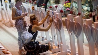 People visit the memorial that has pictures of some of the victims from the partially collapsed 12-story Champlain Towers South condo building on July 15, 2021 in Surfside, Florida. 92 victims have been identified as the search and recovery effort nears completion.