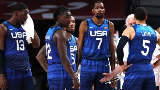 Members of the U.S. men's basketball team stand in blue jerseys with the letters "USA" across the front.