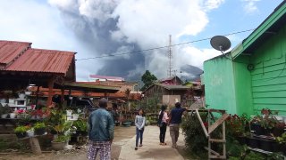 People watch as Mount Sinabung spews volcanic materials during an eruption in Karo, North Sumatra, Indonesia