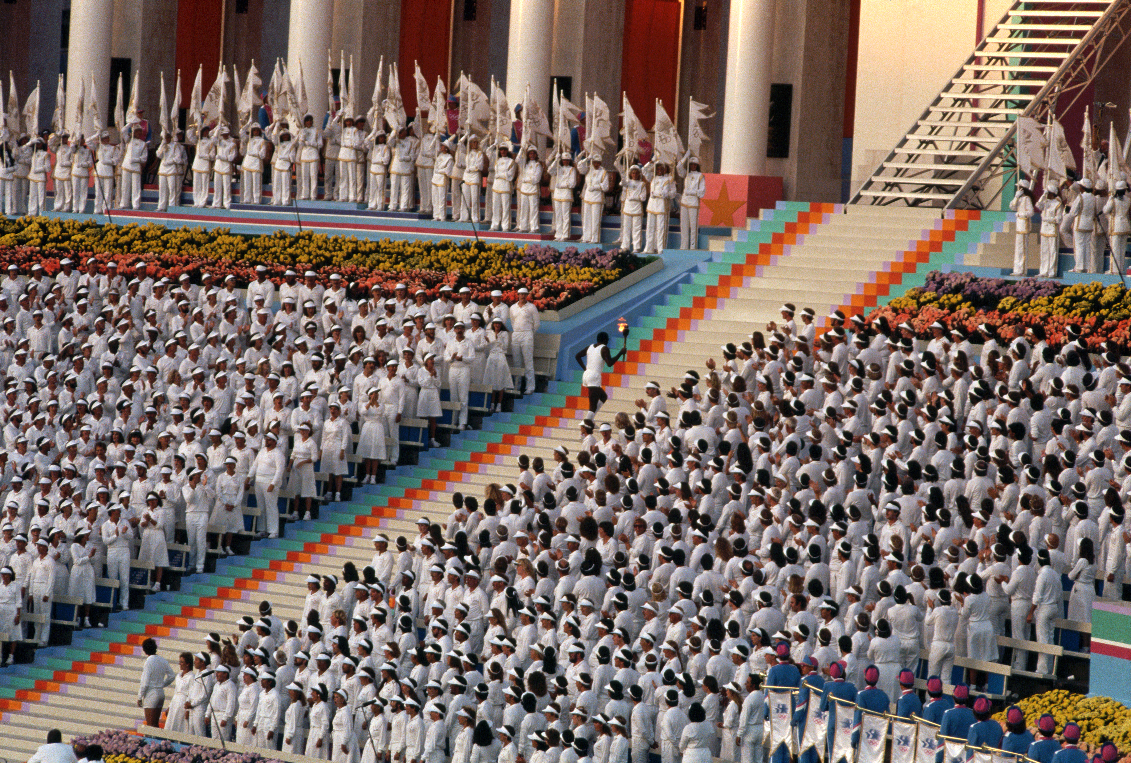 A torchbearer ascends a long stairway carrying a torch to light the Olympic flame at the 194 Opening Eeremony. Many communist nations boycotted the Games that year, notably the USSR, East Germany, and Cuba, as retaliation for the US-led boycott of the 1980 Summer Games in Moscow.   (Photo by David Turnley/Corbis/VCG via Getty Images)