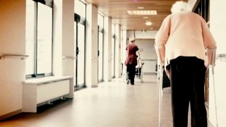 Woman using walker in nursing home hallway