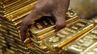 An employee arranges one kilogram gold bars for a photograph in Bangkok, Thailand, on January 13, 2016.