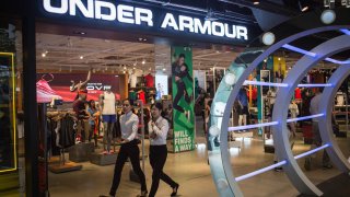 People walks past a Under Armour clothing store in Siam Center, Bangkok.