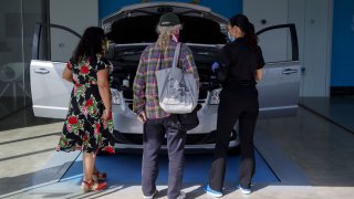 Customers inspect a Fiat Chrysler Automobiles NC Dodge Grand Caravan minivan at a Carvana Co. location in Westminster, California, U.S., on Thursday, May 28, 2020.