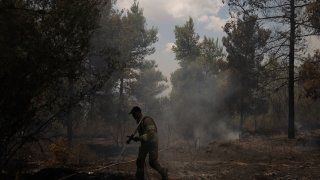 An Israeli firefighter works to extinguish a fire, on the second day of wildfires near Jerusalem, Monday, Aug. 16, 2021. Israel Fire and Rescue service said in a statement on Monday, that 45 firefighting teams accompanied by eight planes were working to contain five fires in the forested hills west of the city.