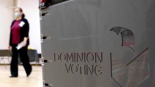 a worker passes a Dominion Voting ballot scanner while setting up a polling location at an elementary school in Gwinnett County, Ga.