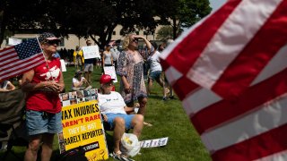 Demonstrators gather with flags and signs to protest against mandated vaccines outside of the Michigan State Capitol on August 6, 2021 in Lansing, Michigan.