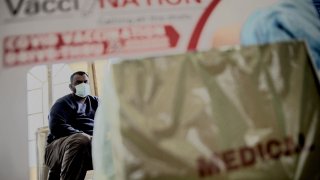 A South African man seats as he waits for his first dose of Pfizer Covid-19 vaccine, in Zwartkops Raceway drive-through vaccination site in Centurion on August 13, 2021.