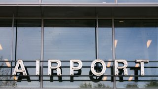 Close-up of text “AIRPORT” above the entrance of an airport. Both neon letters and windows are weathered !