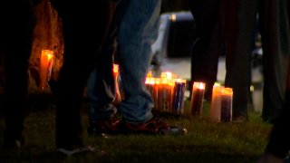 candles seen between people's legs at a vigil in Waterbury