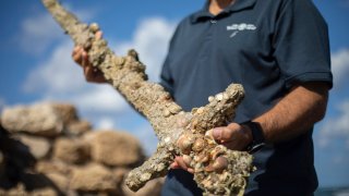 The director of the Marine Archaeology Unit of the Israel Antiquities Authority holds a meter-long (yard-long) sword, that experts say dates back to the Crusaders