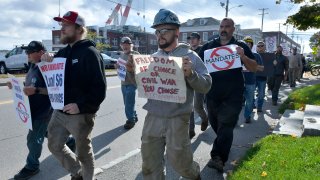 Justin Paetow, center, a tin shop worker at Bath Iron Works, takes part in a demonstration against COVID-19 vaccine mandate outside the shipyard on Friday, Oct. 22, 2021, in Bath, Maine