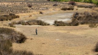 FILE - In this Friday, Sept. 24, 2021 file photo, a shepherd stands in the dry riverbed at Colesberg, Northern Cape, South Africa. According to a United Nations report released on Tuesday, Oct. 5, 2021, much of the world is unprepared for the floods, hurricanes and droughts expected to worsen with climate change and urgently needs better warning systems to avert water-related disasters.