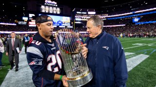 FOXBOROUGH, MA - NOVEMBER 4: This Nov. 4, 2018, file photo shows Red Sox manager Alex Cora hand the World Series trophy to head coach Bill Belichick of the New England Patriots before a game against the Green Bay Packers at Gillette Stadium in Foxboro, Massachusetts.