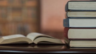 Books stack and book open on desk in library