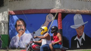 A motorcyclist rides past a mural of Nicaraguan President Daniel Ortega, left, and revolutionary hero Cesar Augusto Sandino during general elections in Managua, Nicaragua, Sunday, Nov. 7, 2021.