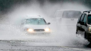 A westbound car is caught in a spray of water thrown up by a pickup truck on Highway 20 Monday, Nov. 15, 2021, near Hamilton, Wash. The heavy rainfall of recent days will brought major flooding of the Skagit River that is expected to continue into at least Monday evening.