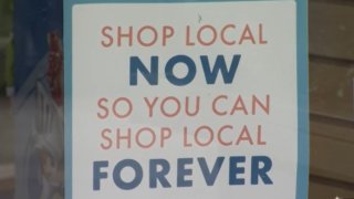 Sign reads 'Shop local now so you can shop local forever'