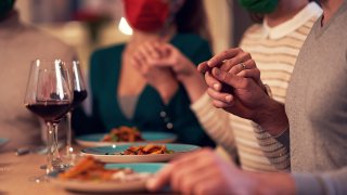 Foto de personas agarradas de manos durante una cena