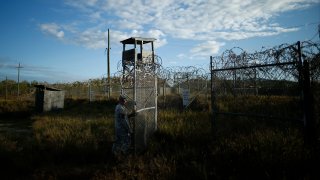 a soldier closes the gate at the now abandoned Camp X-Ray