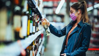 Young female looking at wine to buy in a supermarket.