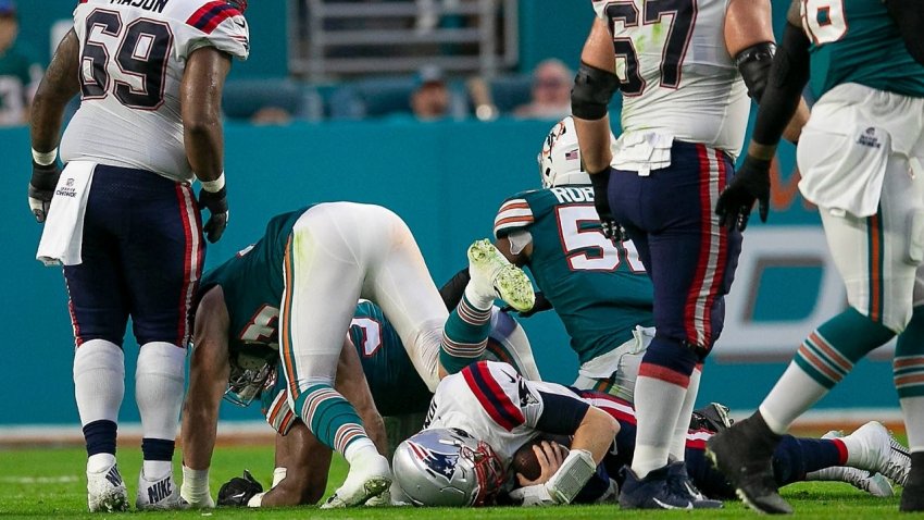 New England Patriots quarterback Mac Jones (10), is sacked during first half action of their game against the Miami Dolphins at Hard Rock Stadium Sunday in Miami Gardens.