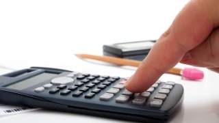 A finger adding up figures using a calculator isolated over a white background.