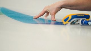 Sweden's Sara Mcmanus slides her fingers on the ice after throwing a rock during a women's curling match against Canada at the Beijing Winter Olympics, Feb. 12, 2022, in Beijing.