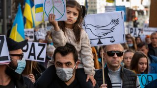 A girl sits on her father shoulders while holding a placard