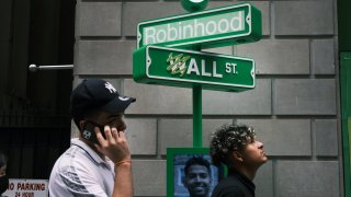 People wait in line for t-shirts at a pop-up kiosk for the online brokerage Robinhood along Wall Street after the company went public with an IPO earlier in the day on July 29, 2021 in New York City.