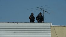 Members of the New York Police Department look on from a rooftop after at least 16 people were injured during a rush-hour shooting at a subway station Brooklyn, New York, on April 12, 2022.