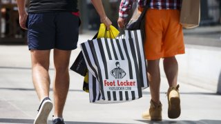 Customers walk with Foot Locker shopping bags on the Third Street Promenade in Santa Monica, California.