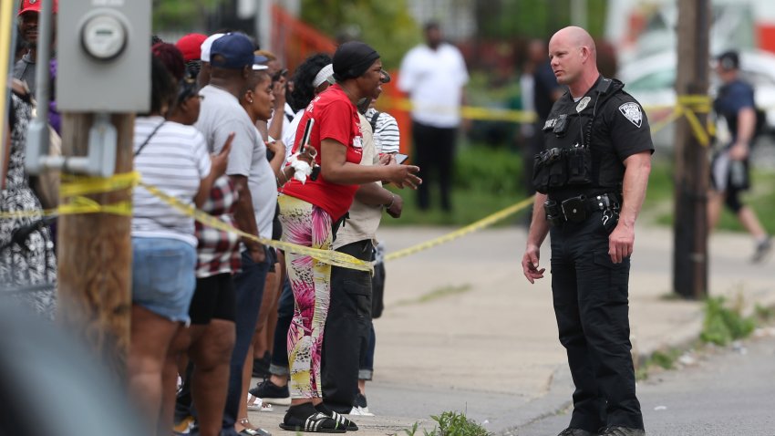 Police speak to bystanders while investigating after a shooting at a supermarket