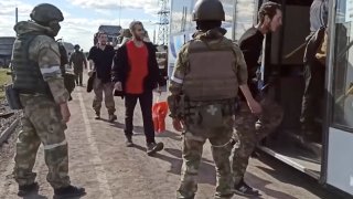 In this photo taken from video released by the Russian Defense Ministry Press Service on Tuesday, May 17, 2022, Russian servicemen watch Ukrainian servicemen boarding a bus as they are being evacuated from the besieged Azovstal steel plant in Mariupol, Ukraine. More than 260 fighters, some severely wounded, were pulled from a steel plant on Monday that is the last redoubt of Ukrainian fighters in the city and transported to two towns controlled by separatists, officials on both sides said.