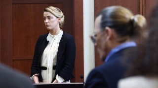 FILE - Amber Heard testifies as Johnny Depp looks on during a defamation trial at the Fairfax County Circuit Courthouse in Fairfax, Virginia, on May 5, 2022.