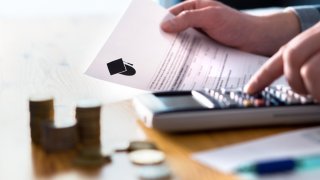 Man counting college savings fund, tuition fee or student loan with calculator. Education price and expenses concept. Money and papers on table. Calculating budget and planning finance.