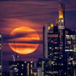 The full moon rises behind buildings in the banking district in Frankfurt, Germany,