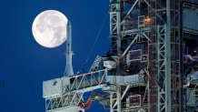 The Strawberry Supermoon sets in front of the NASA Artemis rocket