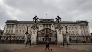 A dog walker passes a quiet Buckingham Palace