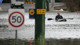 A man paddles his kayak through a flooded street