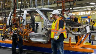 Workers install door hinges to the body shell of a prototype Endurance electric pickup truck on June 21, 2021 at Lordstown Motors assembly plant in Ohio.